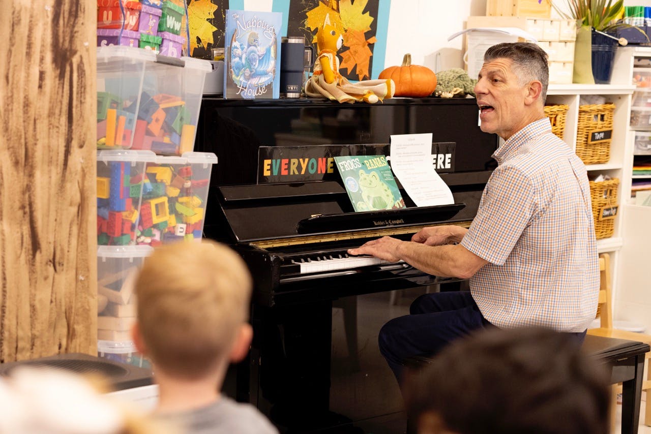 Person playing piano and singing in a classroom