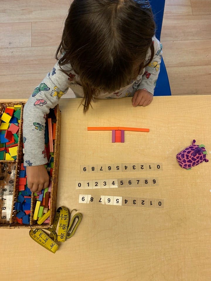 Child playing with colorful blocks and number strips on a table