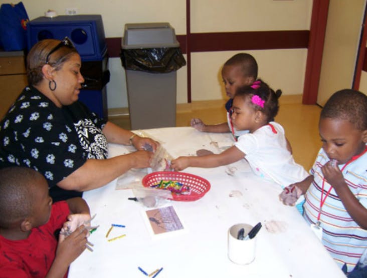 Person and three children at a table with craft supplies