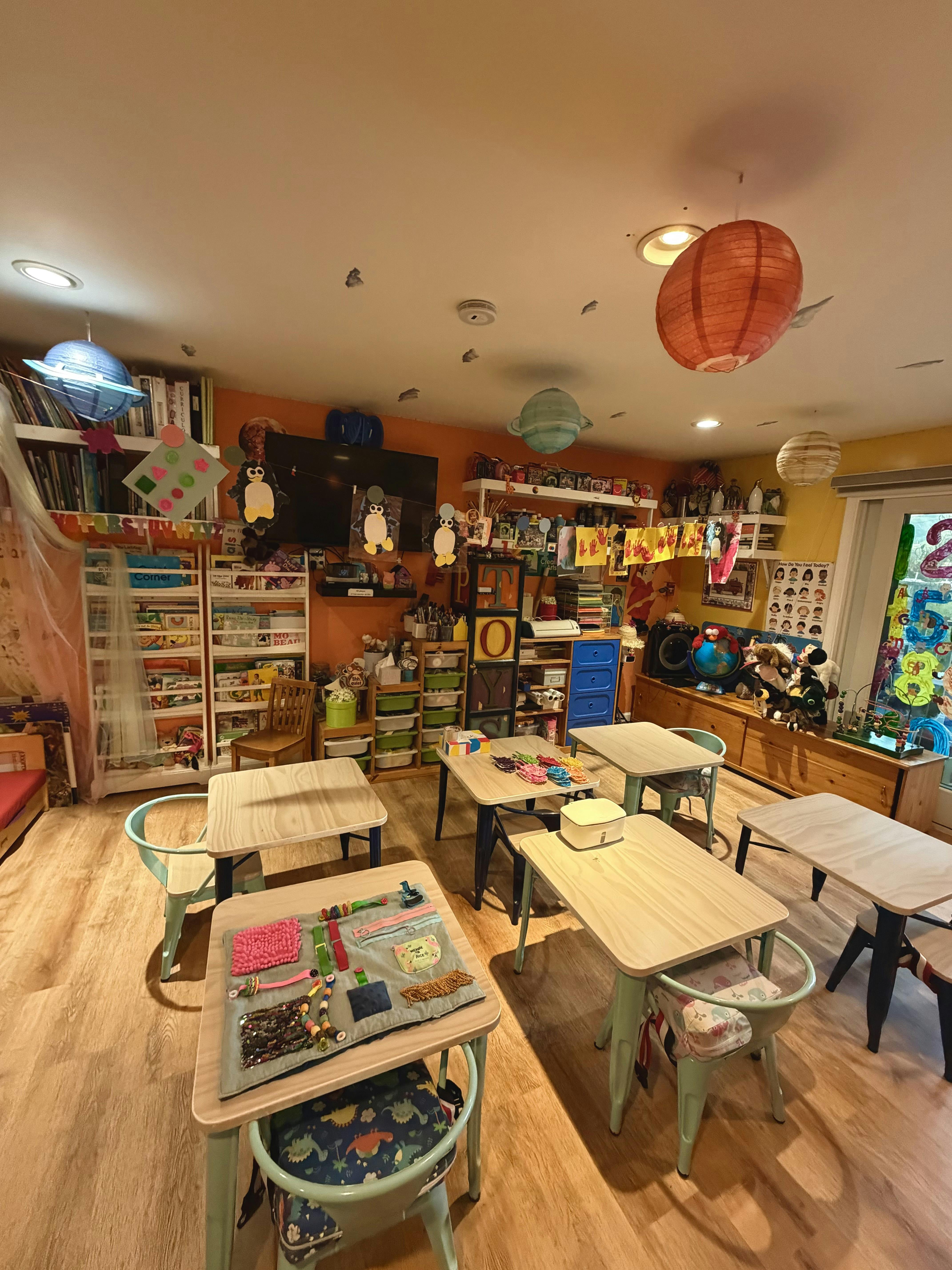 Classroom with small tables and chairs, bookshelves, and decorations