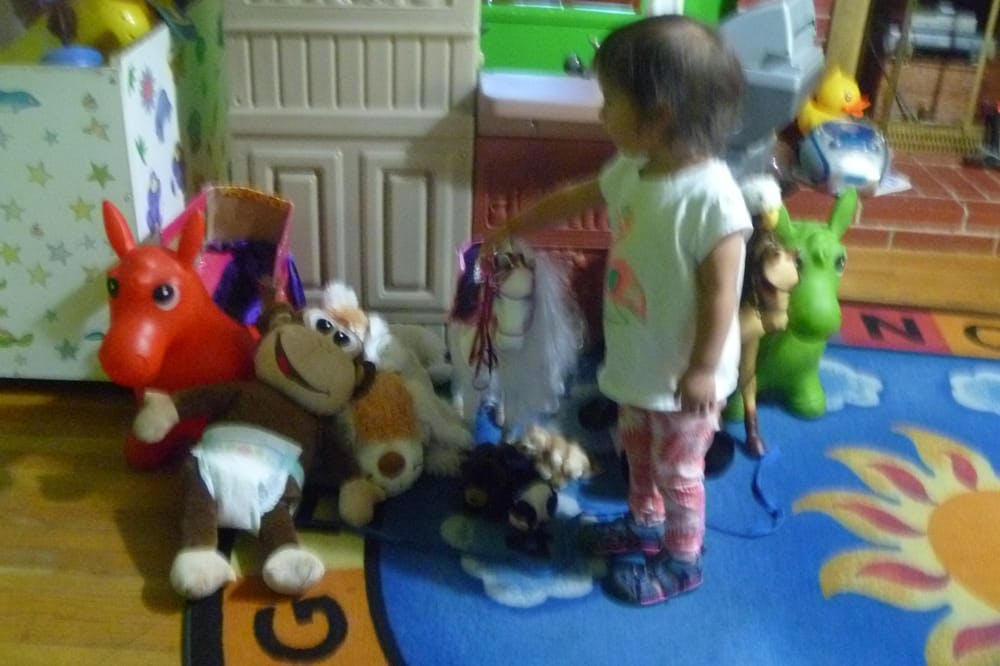 Child standing on a rug with toys