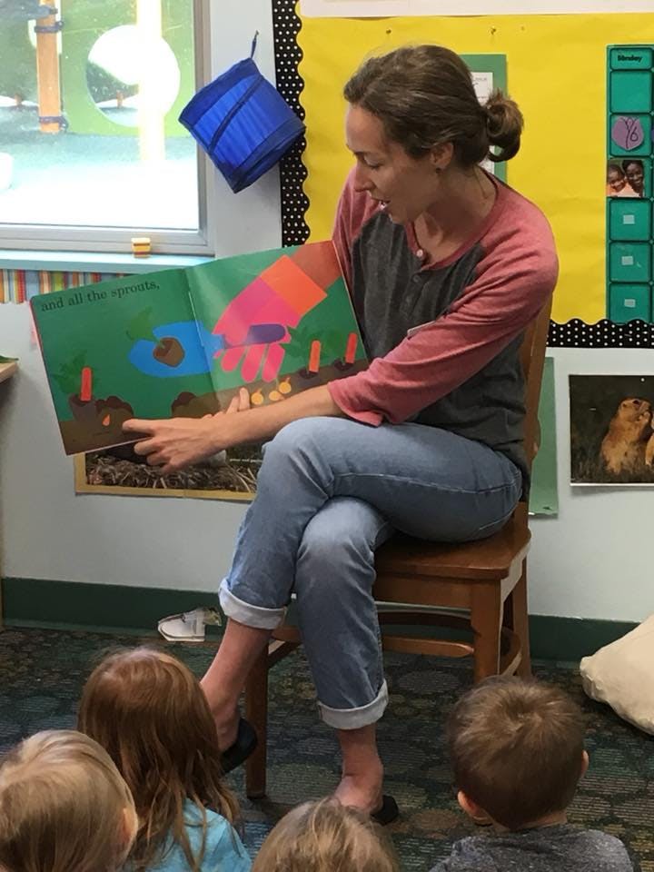 Person reading a book to children in a classroom