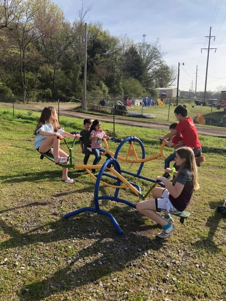 Children playing on a seesaw in a grassy area
