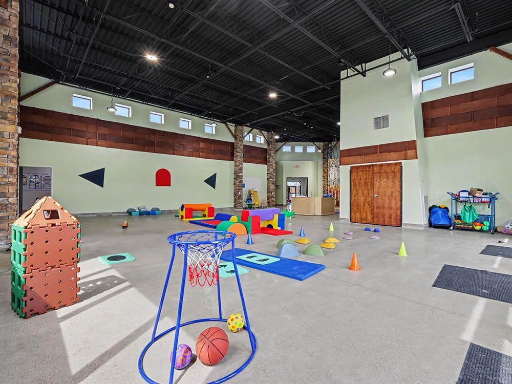 Indoor play area with colorful mats, soft play equipment, and a small basketball hoop