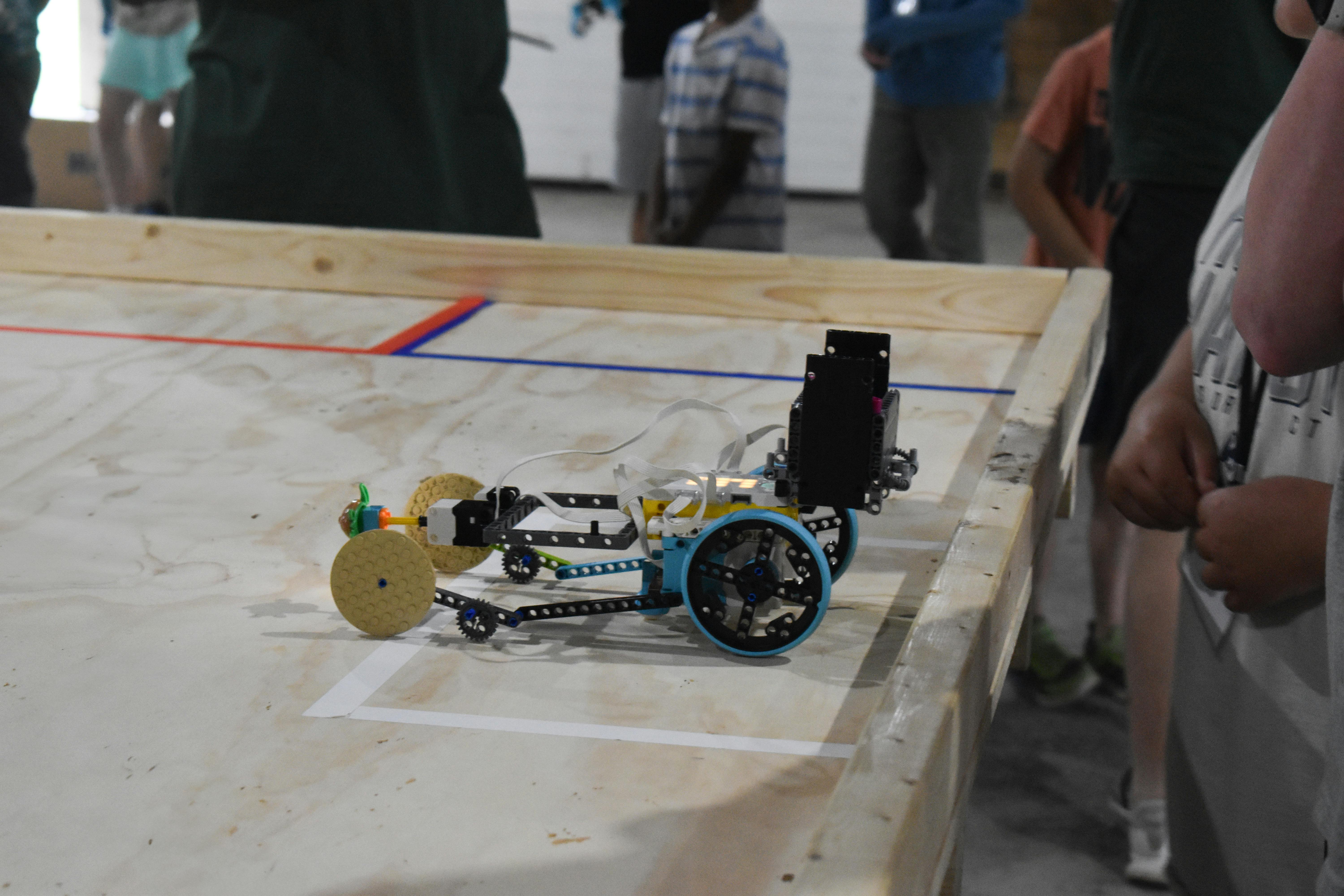 Robotic car on a wooden surface with red and blue lines