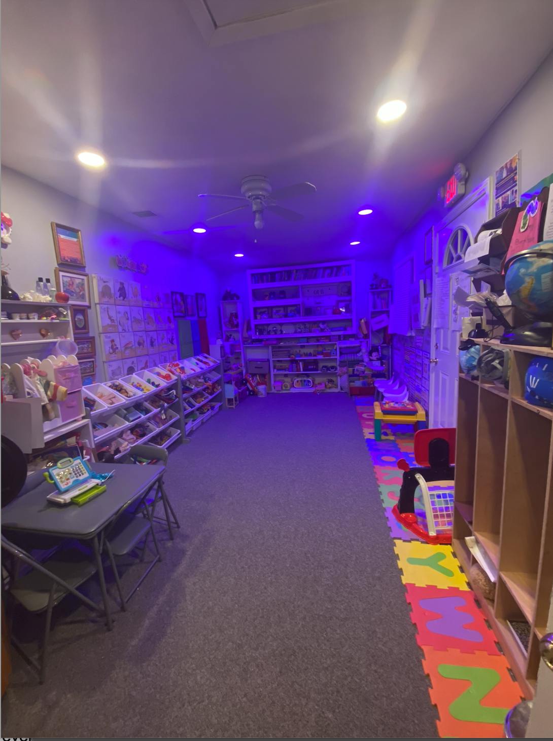 A room with purple lighting, full of toys and learning materials