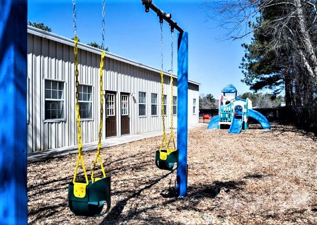 Playground with swings and a slide structure next to a building