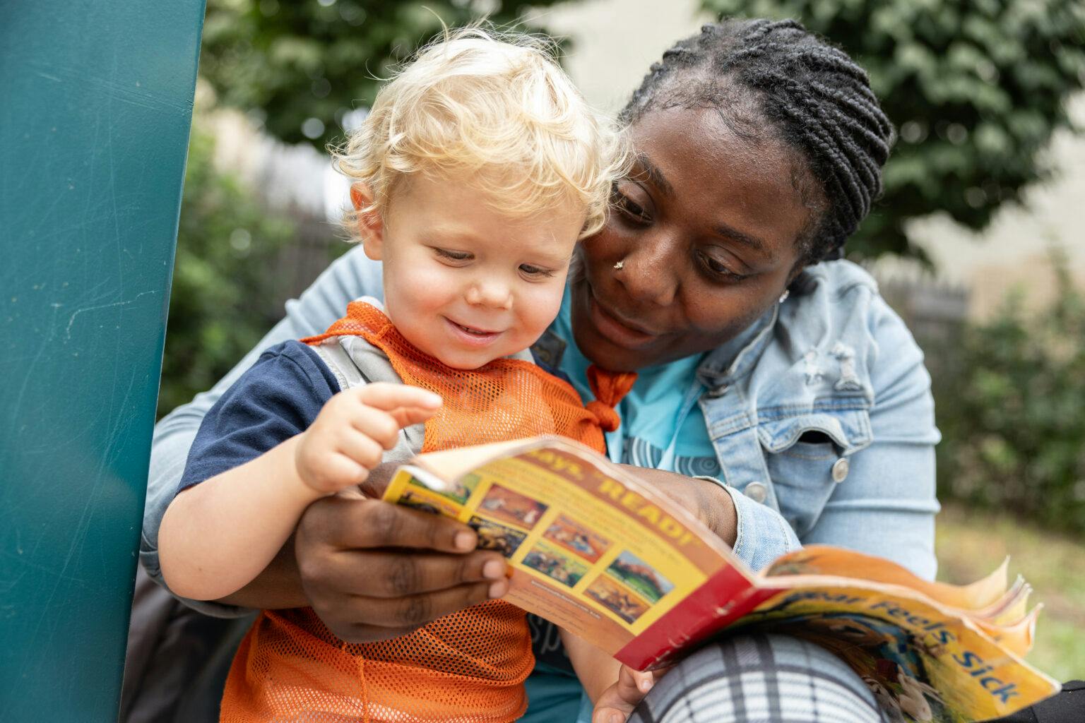 Person and child reading a book together