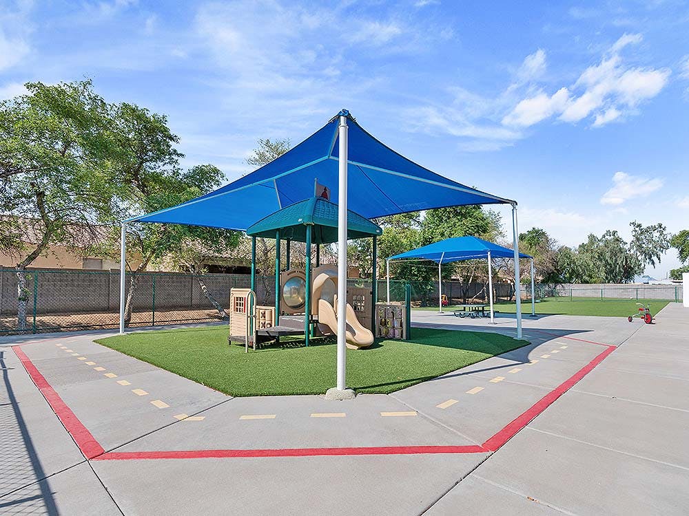 Outdoor playground with blue shade sails over play structures