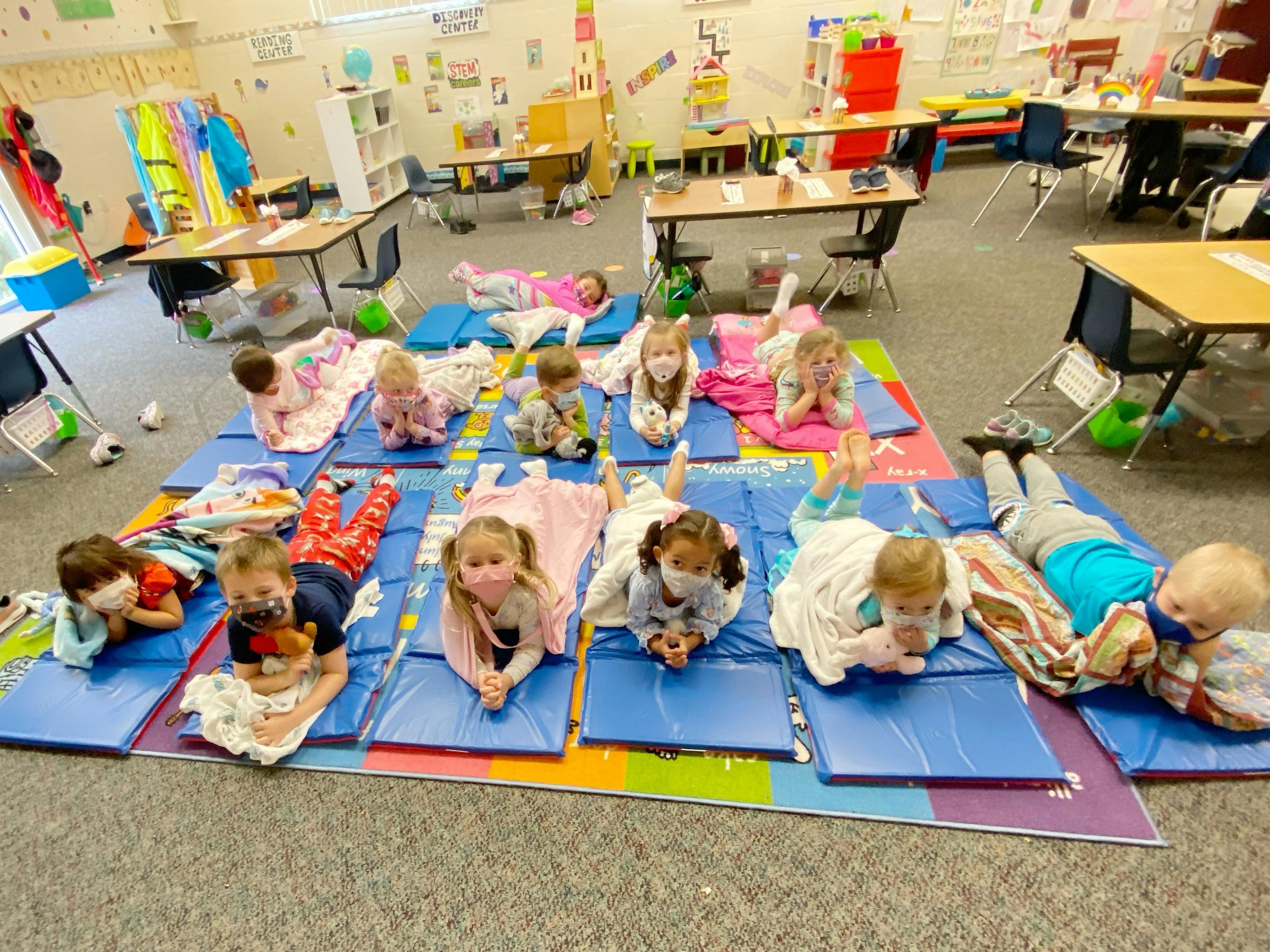 Children lying on mats in a classroom