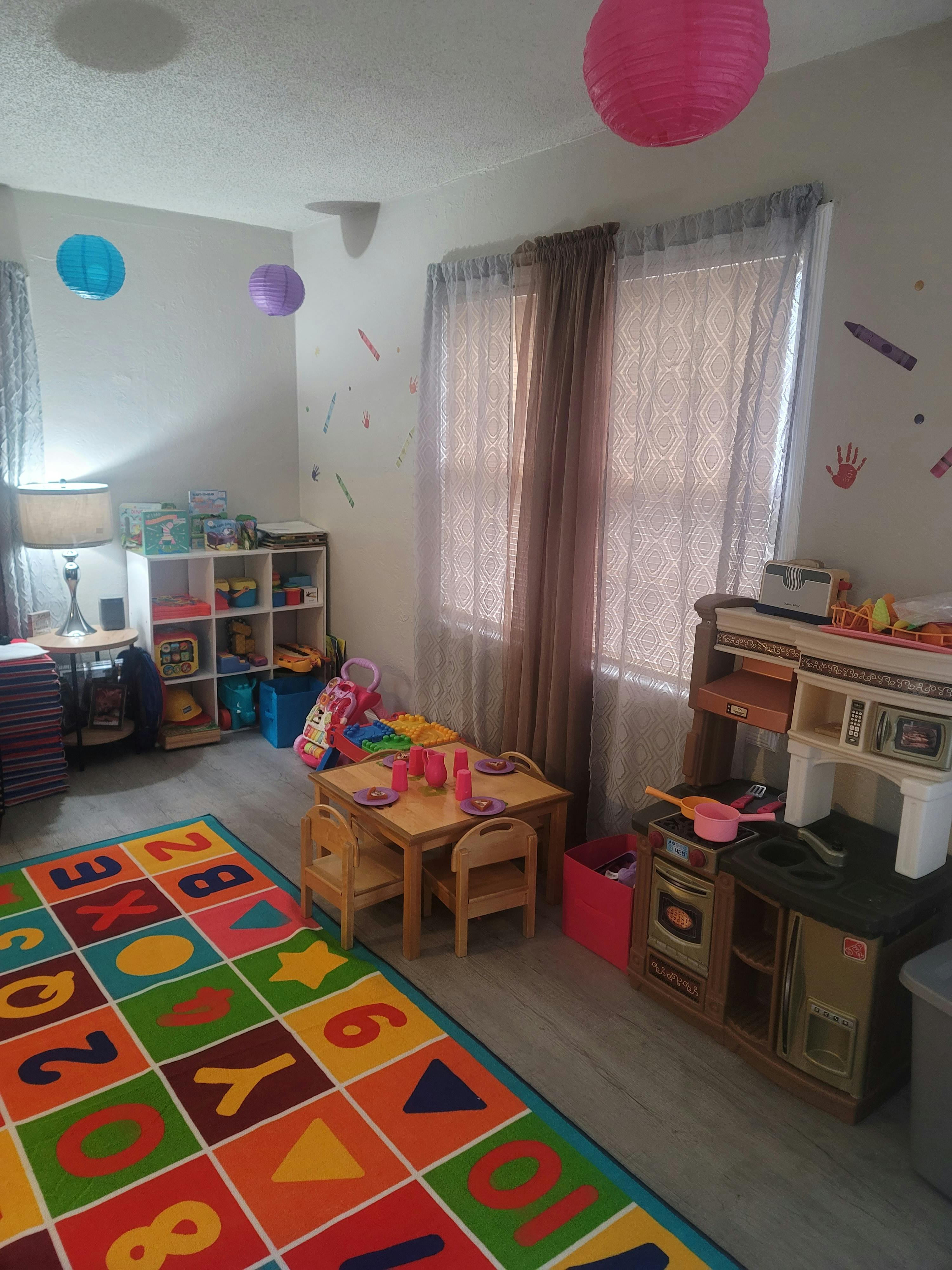 Playroom with a colorful alphabet rug, small table and chairs, and toy kitchen