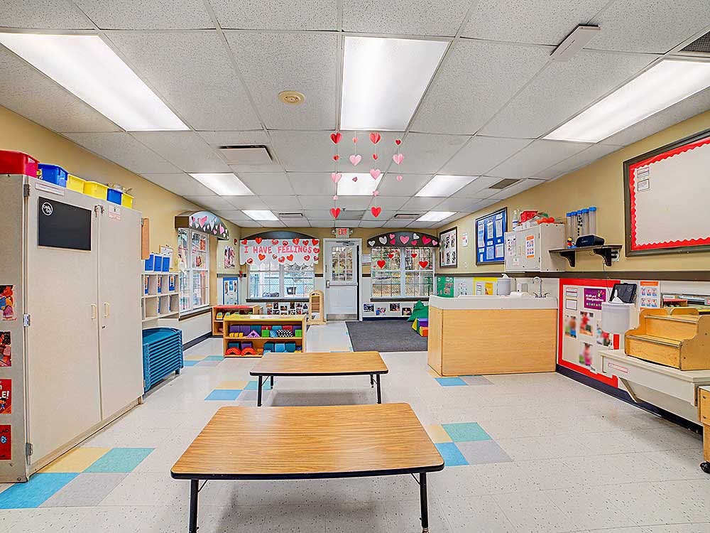 Empty colorful classroom with tables, cupboards, and heart decorations