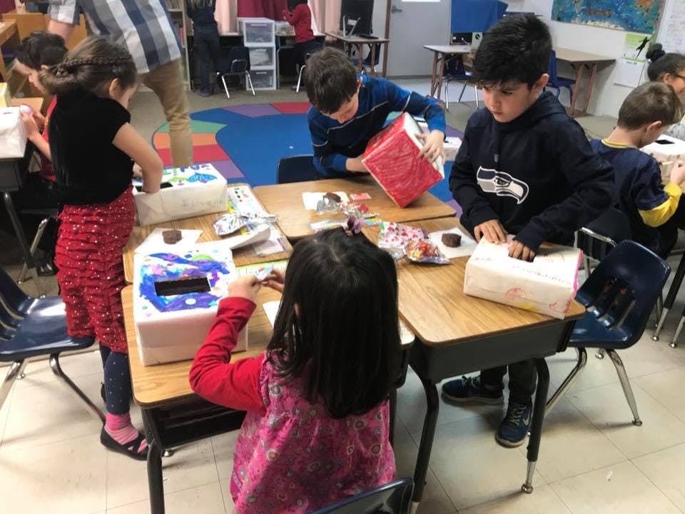 Children working on craft projects at desks in a classroom