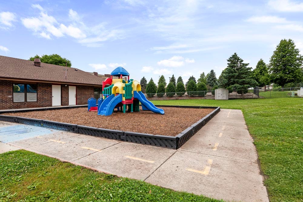 Playground with colorful play structure, slides, and woodchip ground