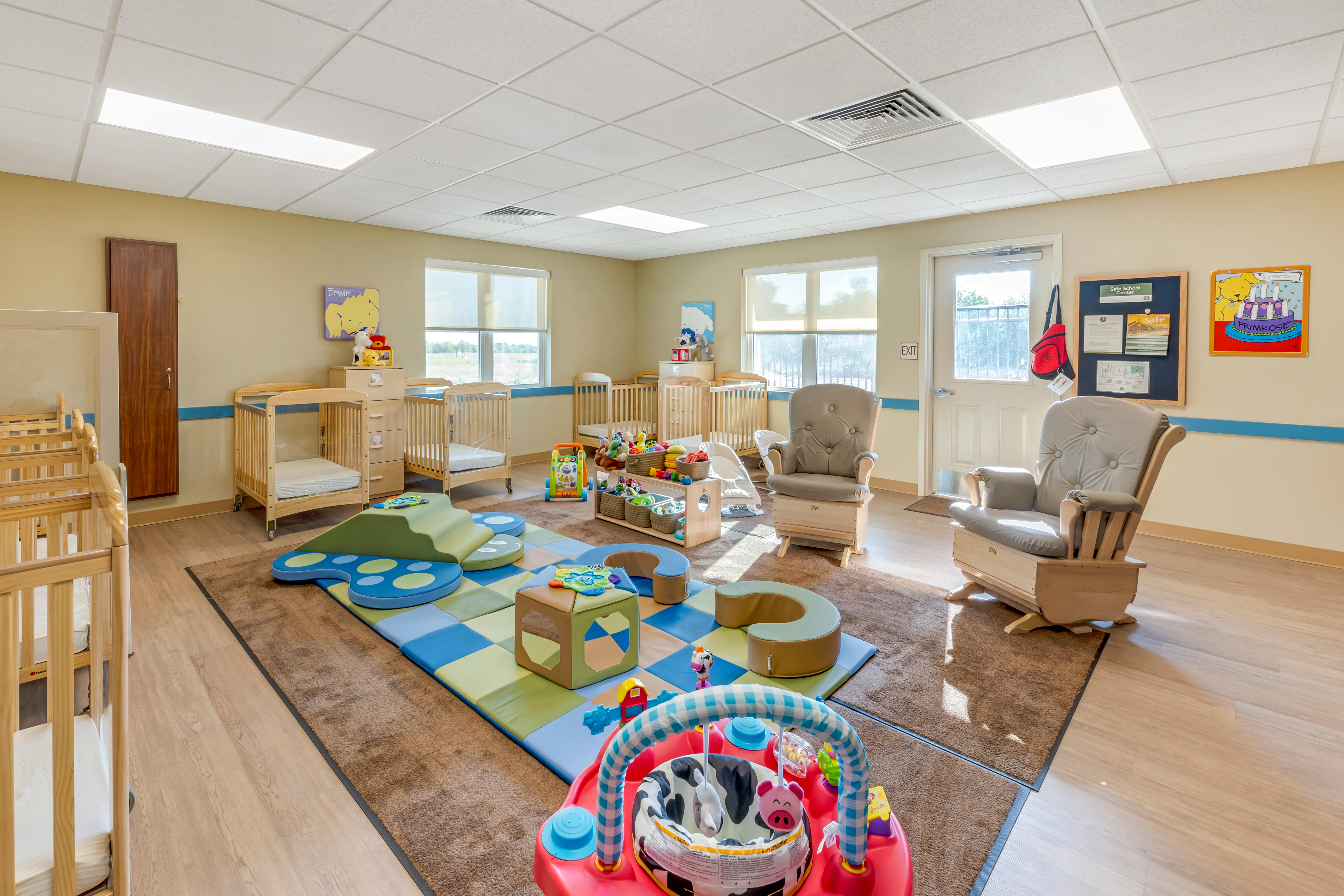 A playroom with cribs, play mats, toys, and two rocking chairs