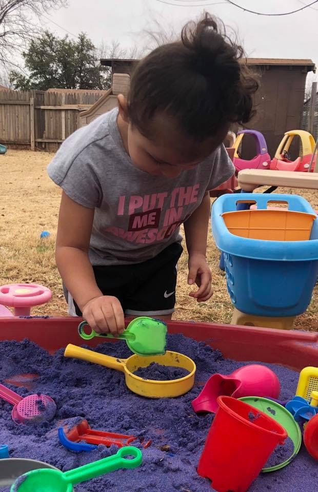 Child playing in a sandbox with sand toys