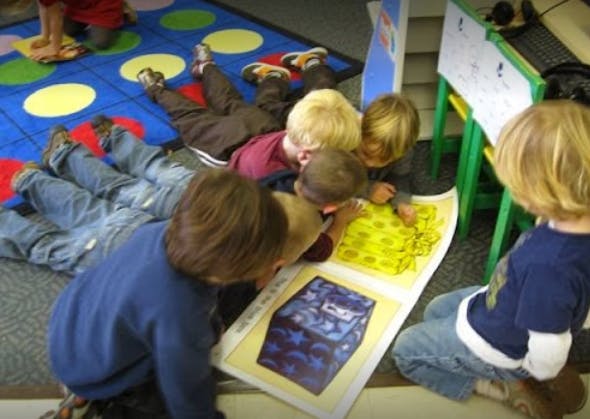 Children gathered around a large open book on the floor