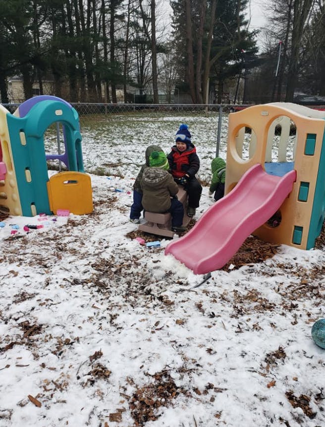 Children playing on playground equipment in the snow