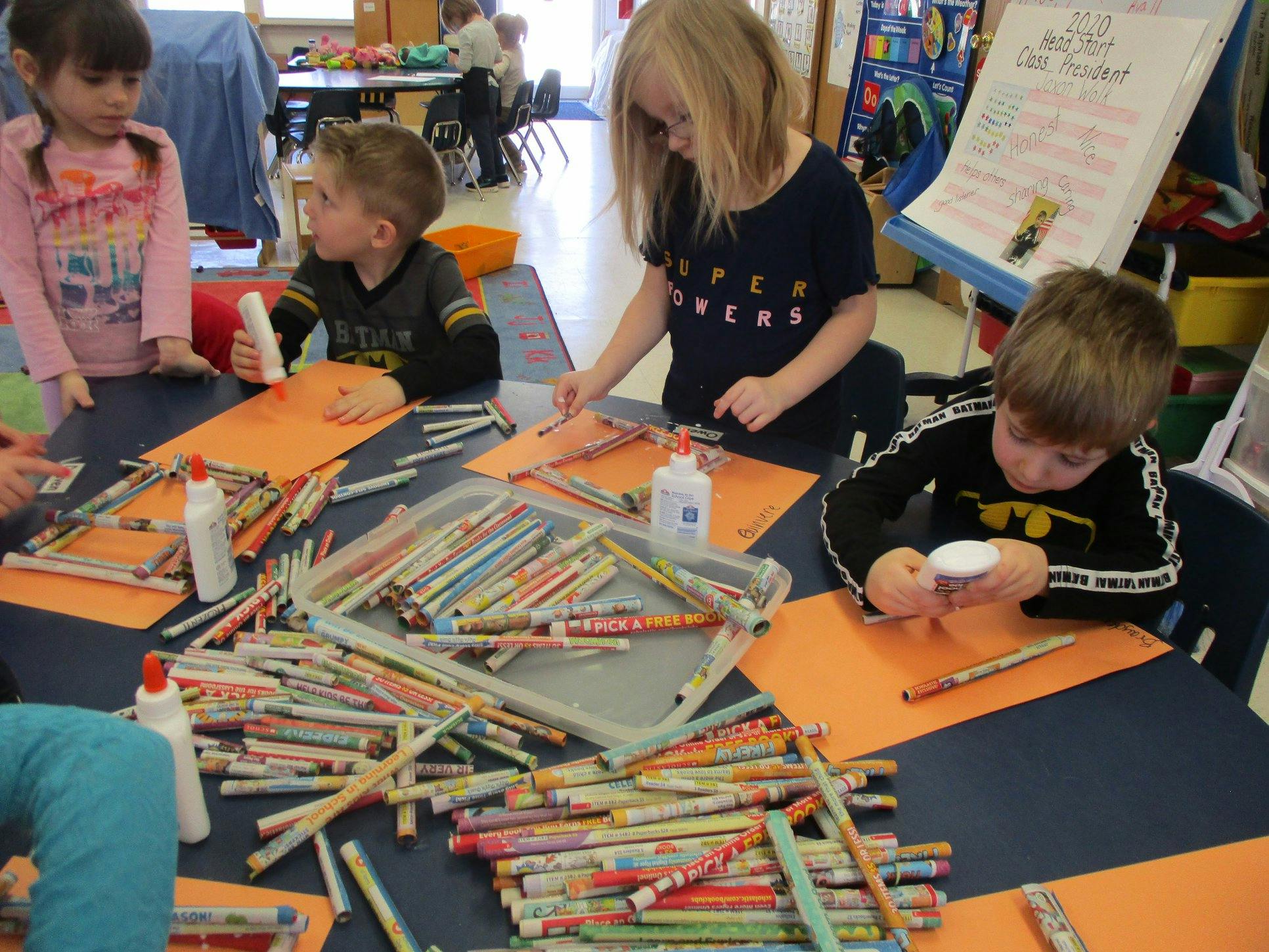 Children doing crafts with paper and glue in a classroom
