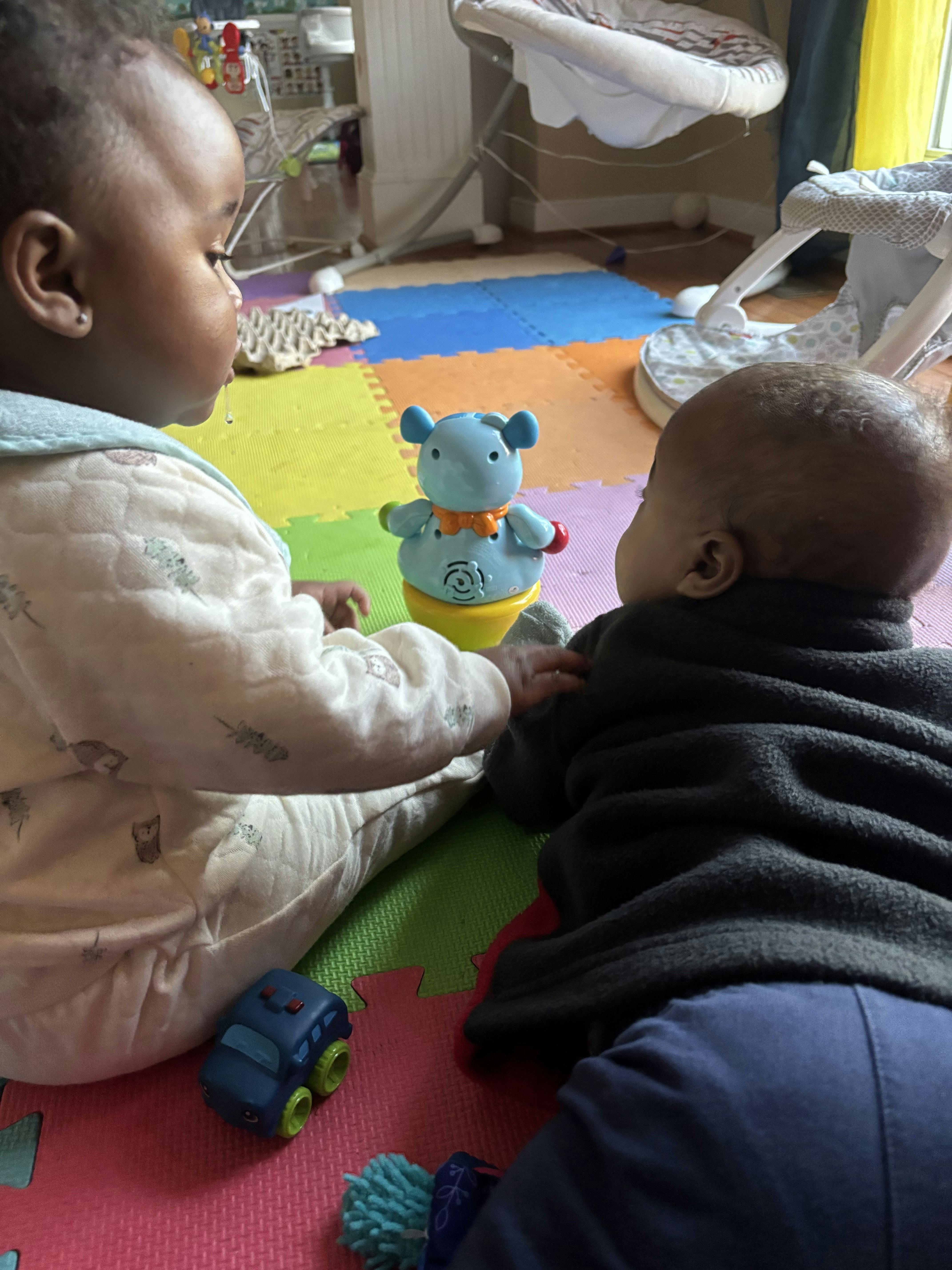 Two children playing with a toy on a colorful foam floor mat