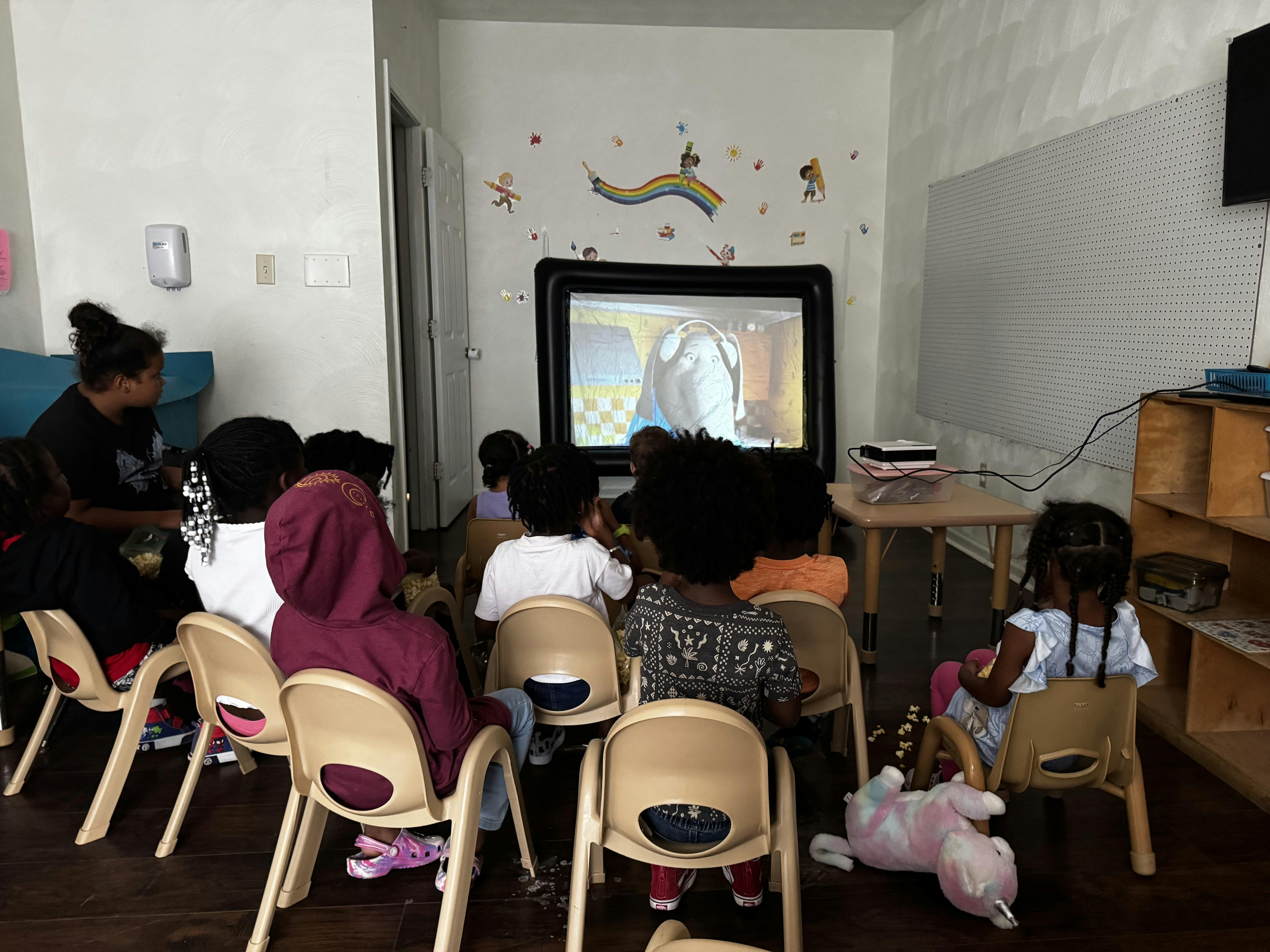 Adult and children watching a television screen in a room