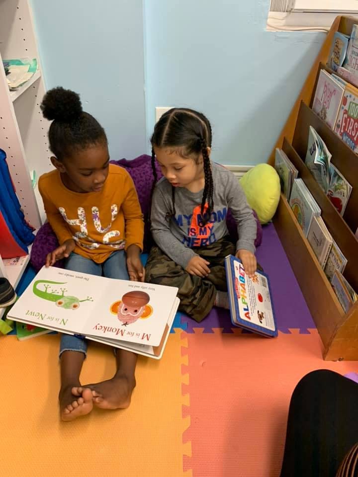 Two children sitting on the floor reading books