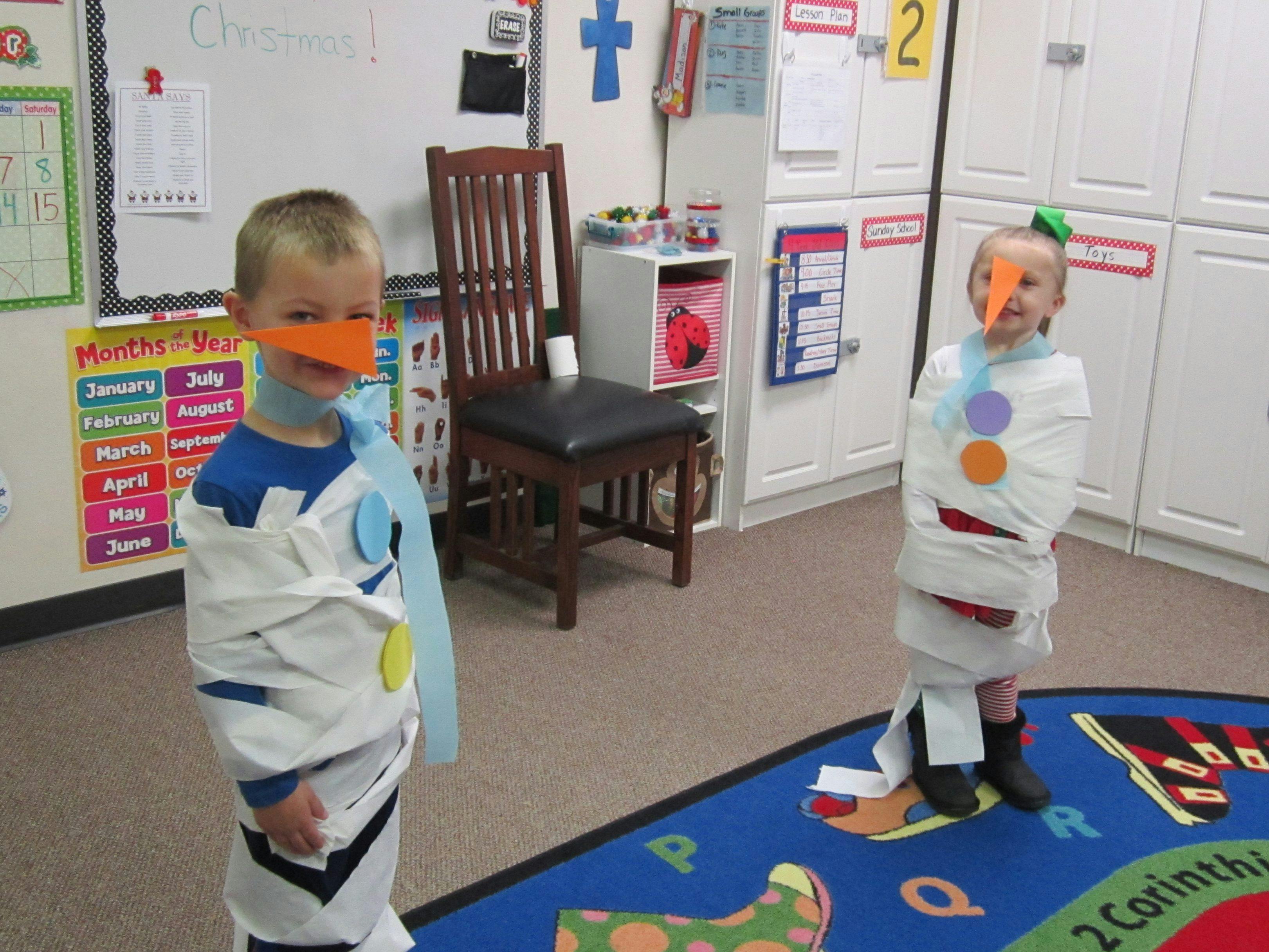 Two children dressed as snowmen with paper wrapped around them