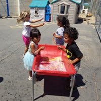 Four children playing at a water table outdoors