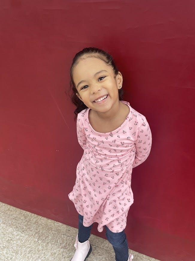 Child smiling in a pink floral top and jeans