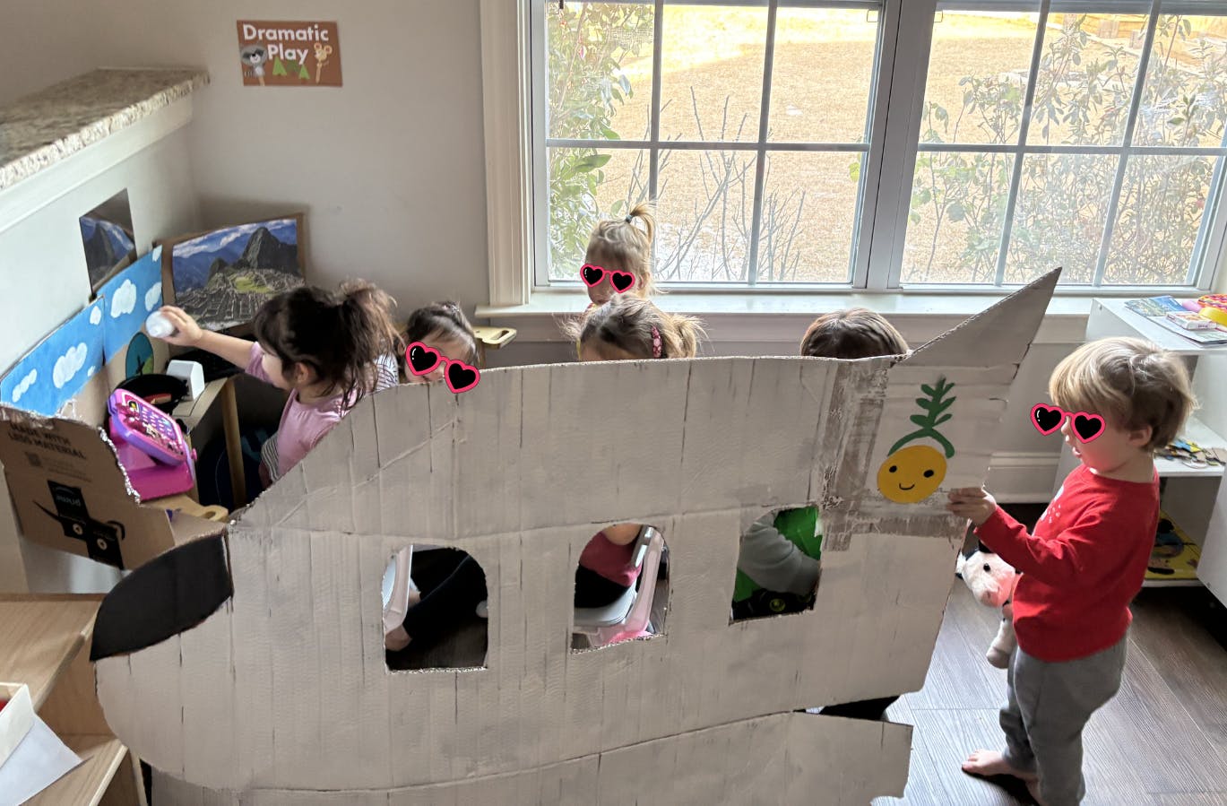 Children playing in a classroom with a large cardboard airplane