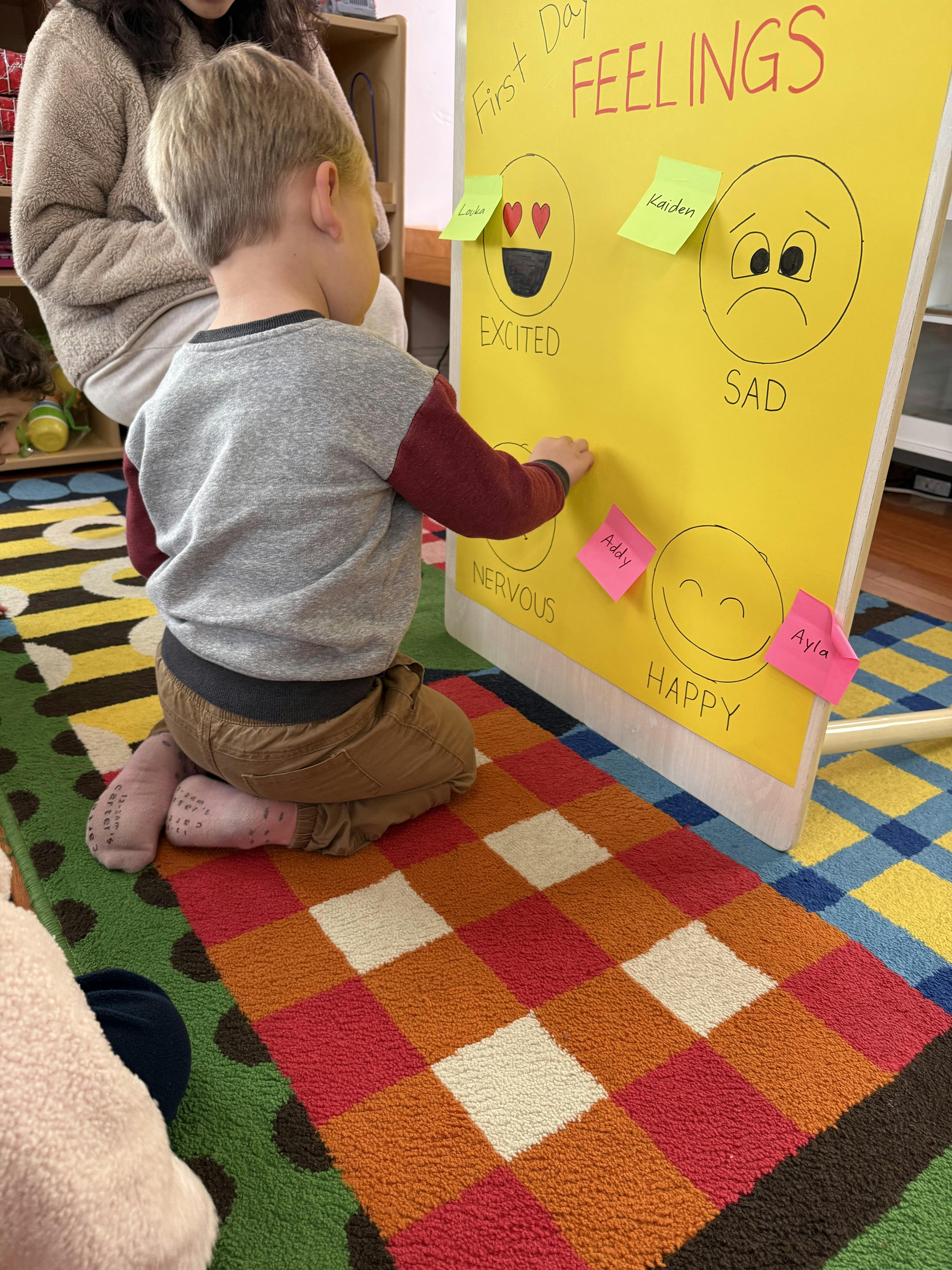 Child placing a sticky note on a feelings chart in a classroom