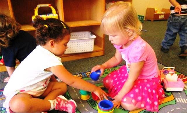 Two children playing with toys on a rug