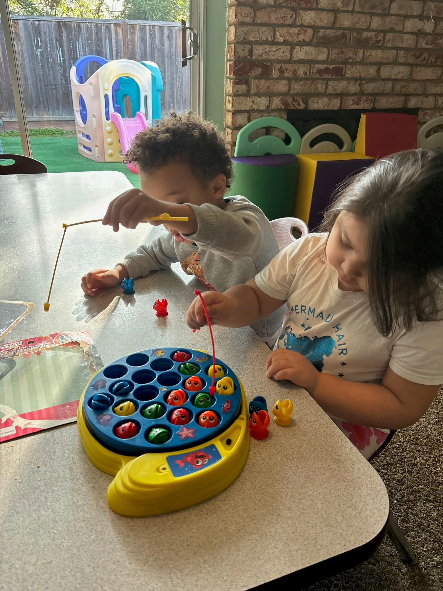 Two children playing with a fishing game on a table