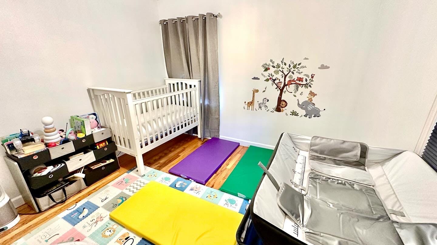Nursery room with a white crib, changing table, and colorful play mats