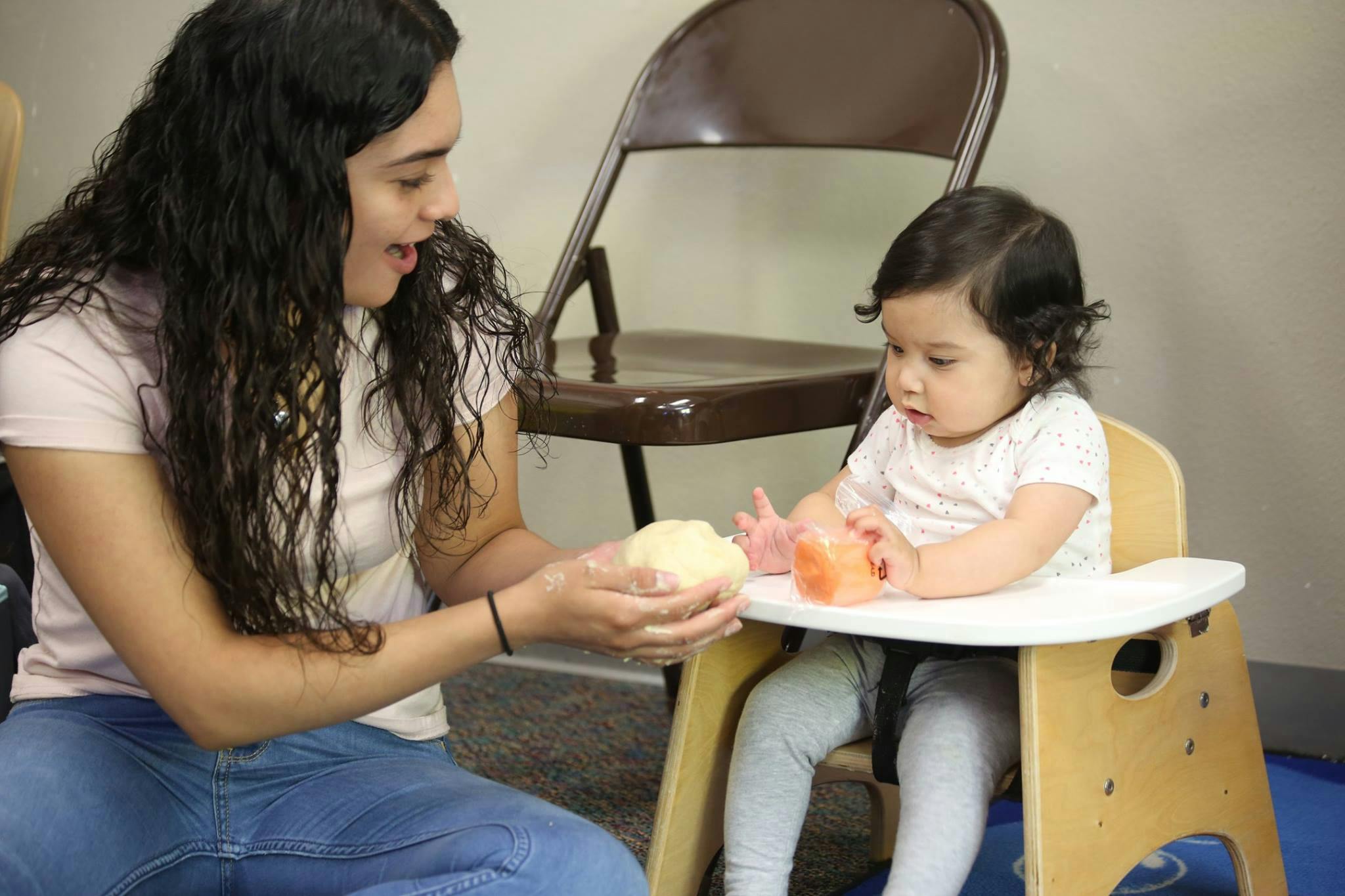 Person holding a toy for a child in a high chair