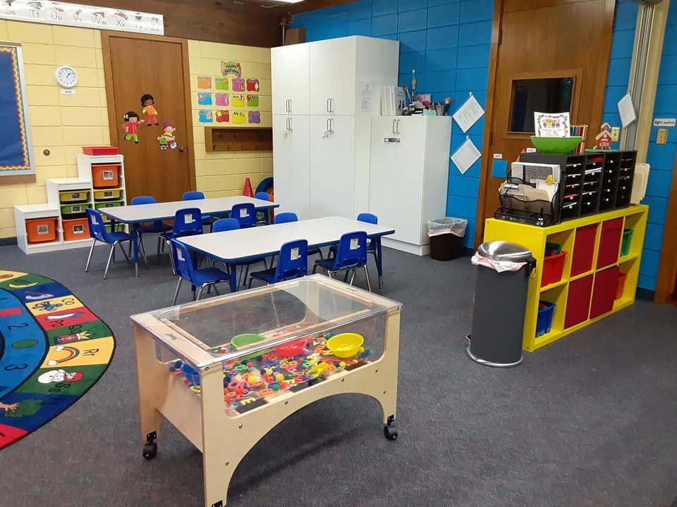 Classroom with tables, chairs, and a sensory bin