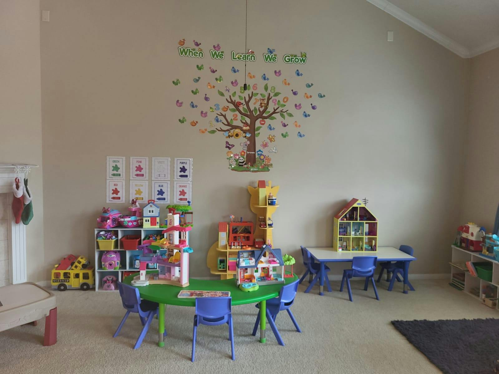 Playroom with tables, chairs, and toys, tree mural on wall