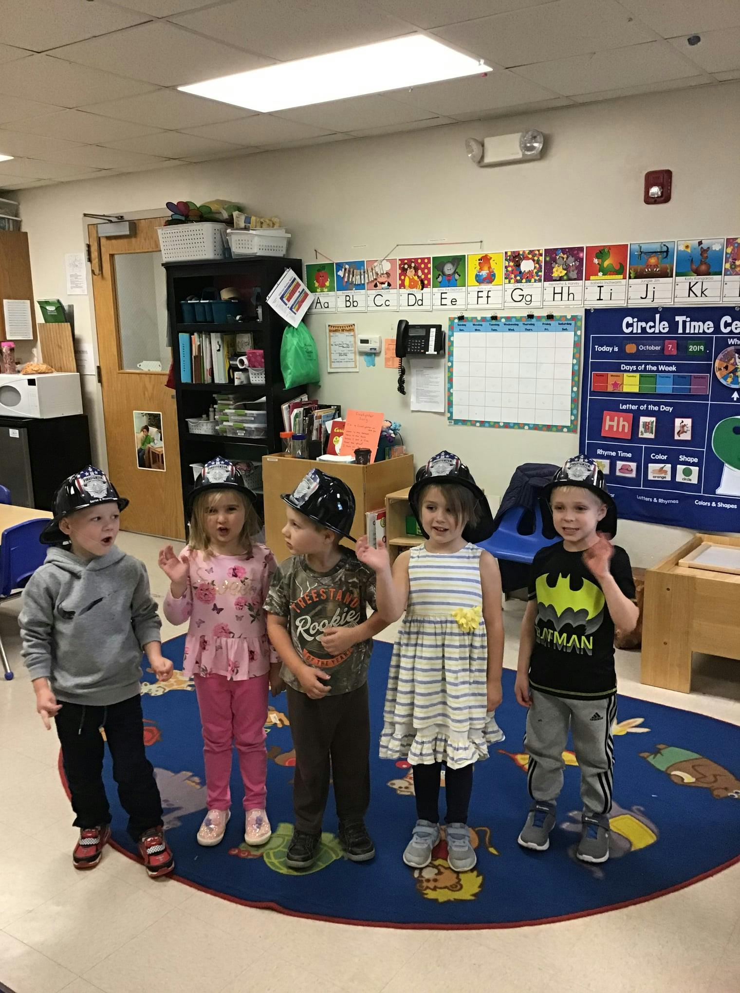 Five children wearing hats in a classroom