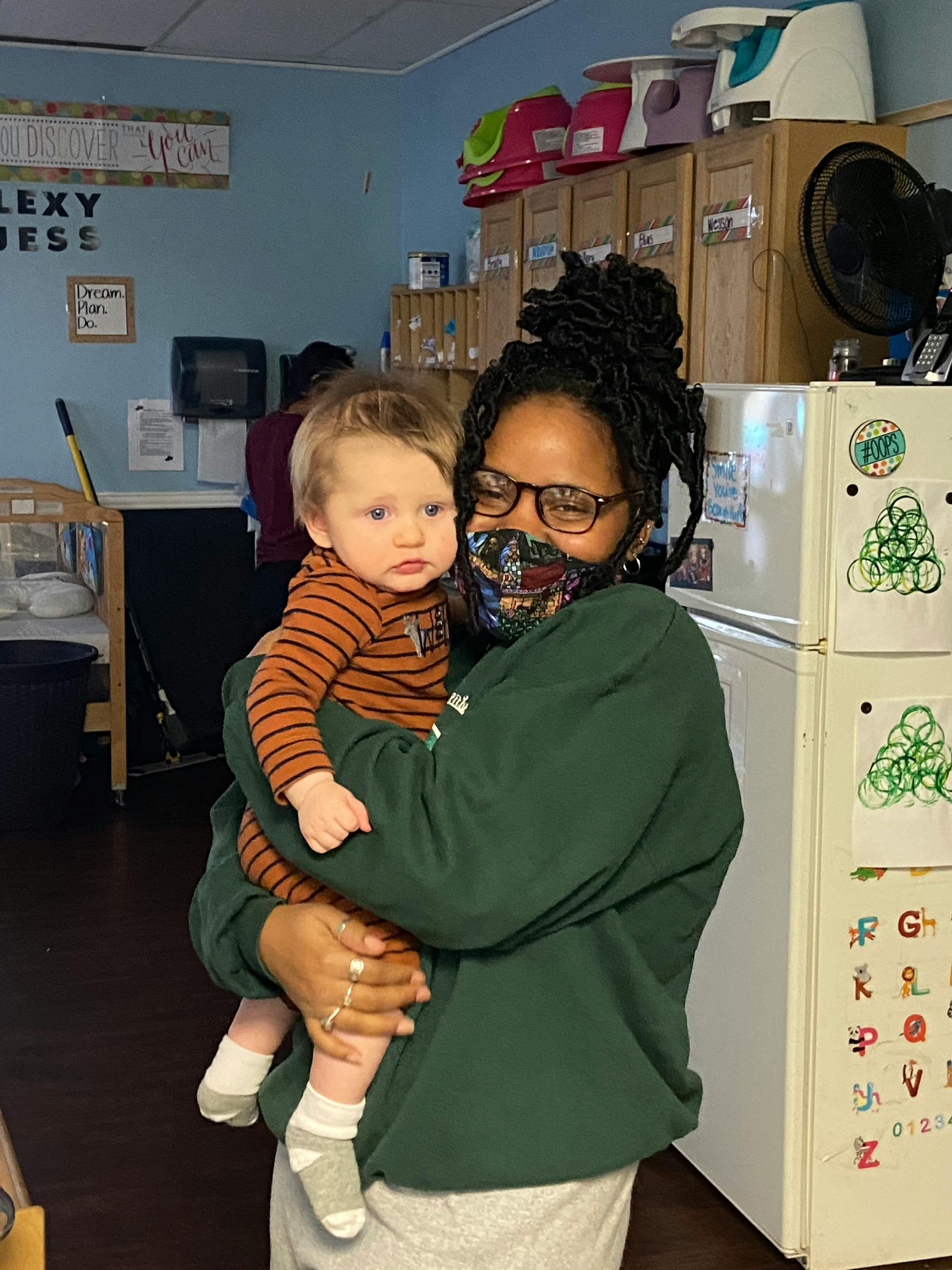 Person wearing glasses and a mask holding a child