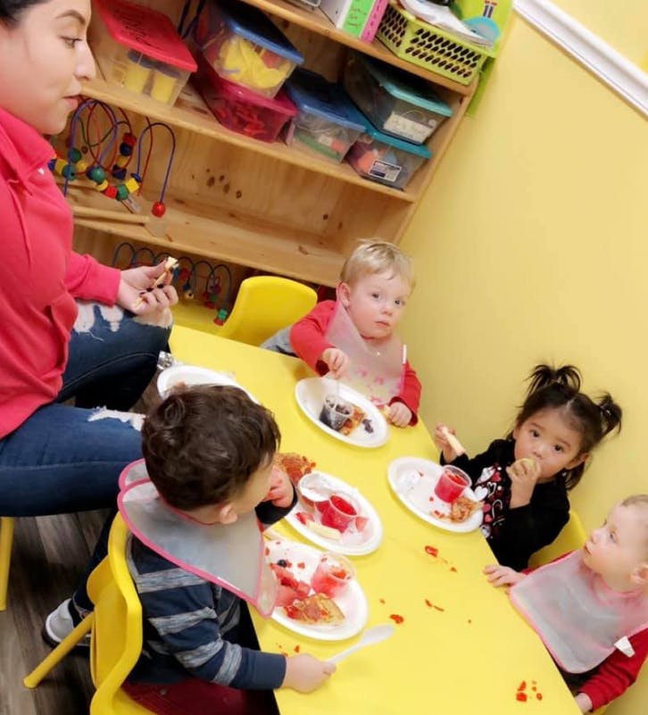 Adult and children eating at a yellow table