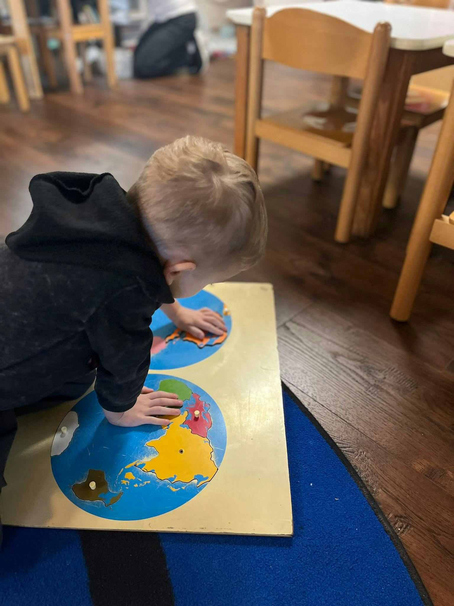 Child playing with a world map puzzle in a classroom