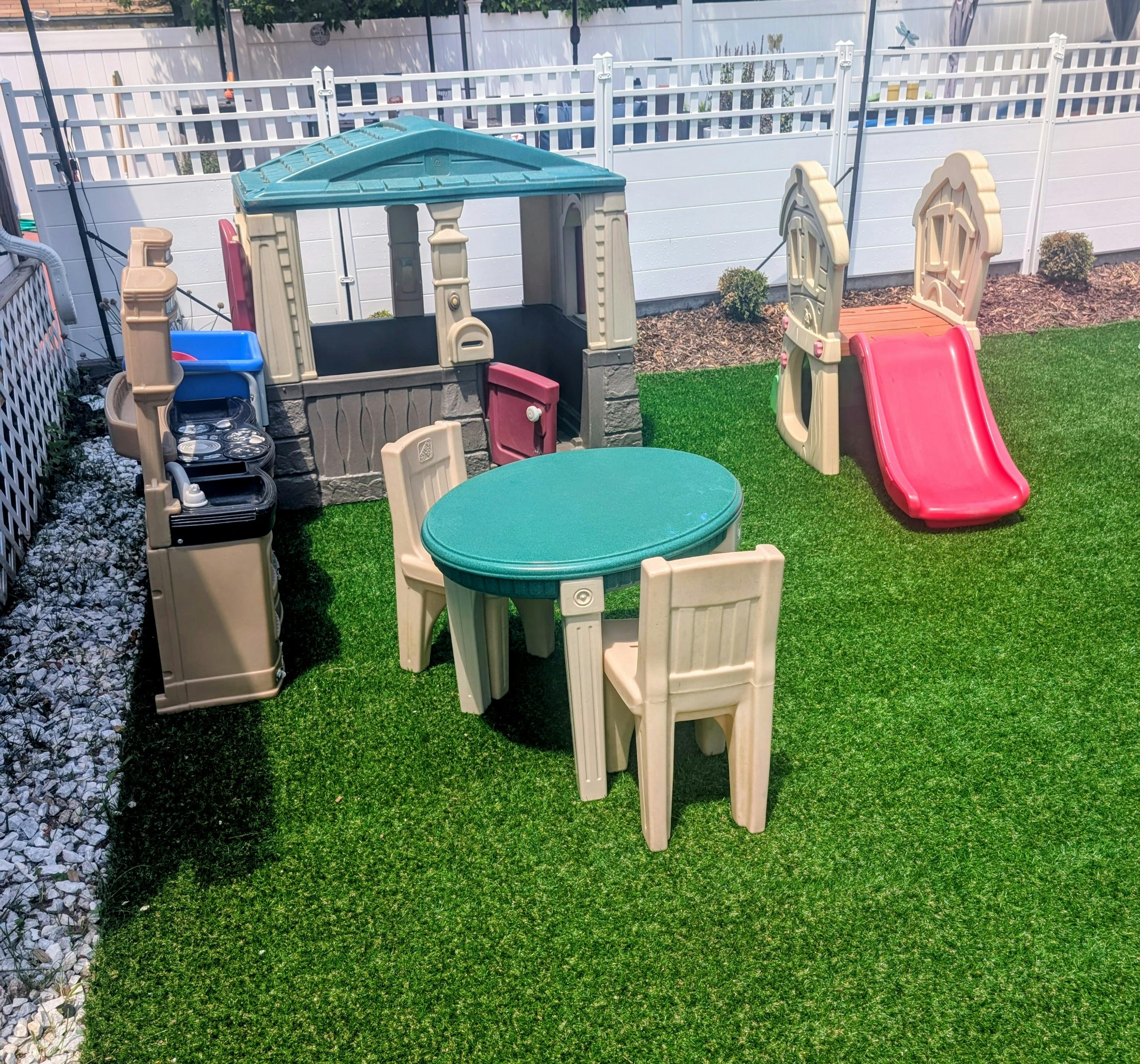 Children's playhouse, slide, and table with chairs on artificial grass