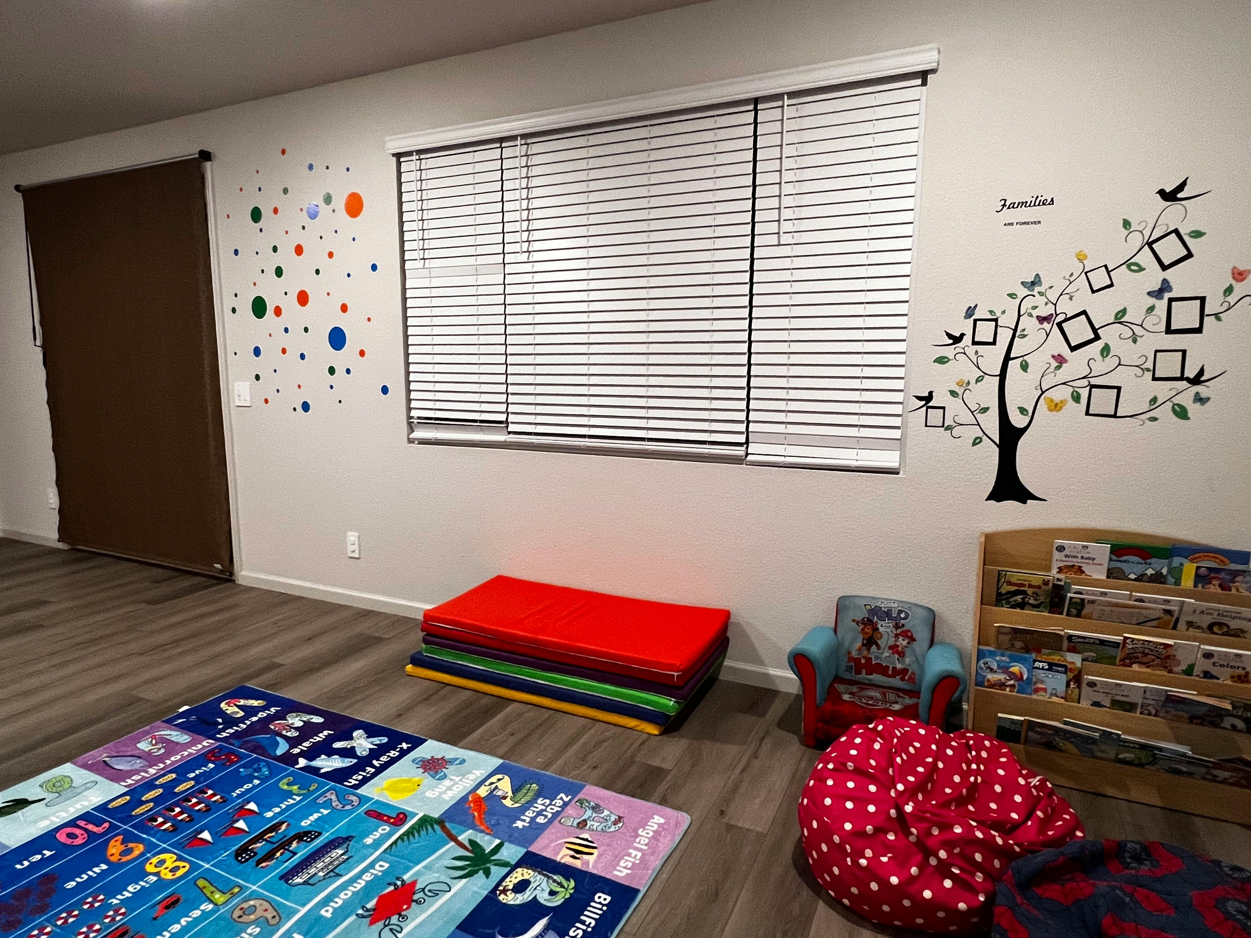 Playroom with colorful floor mat, stacked mats, and wall decals