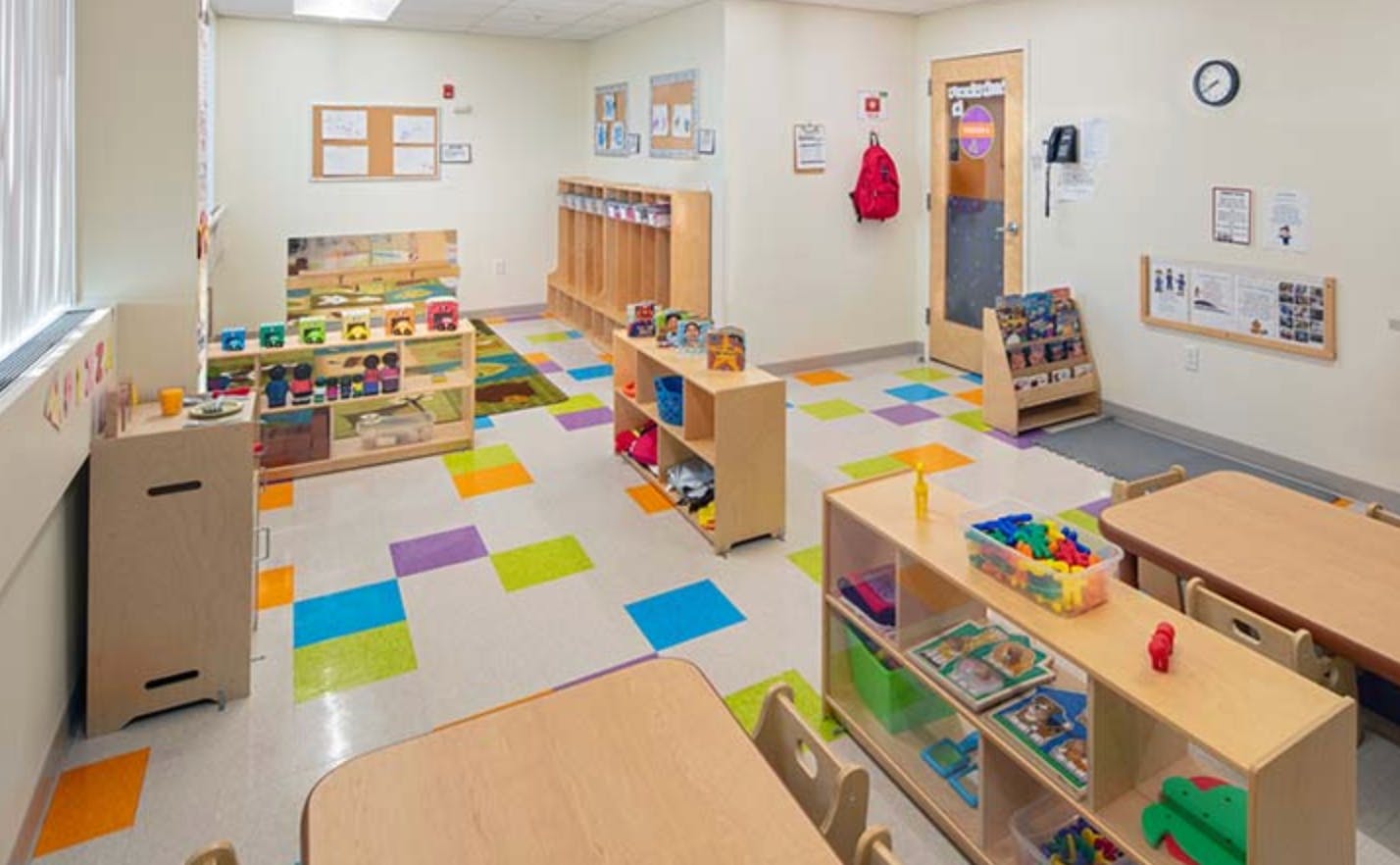 Empty classroom with colorful floor tiles and wooden furniture