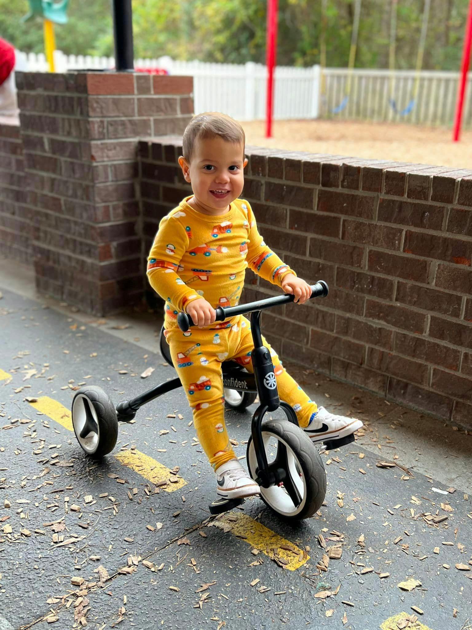 Child riding a tricycle on pavement