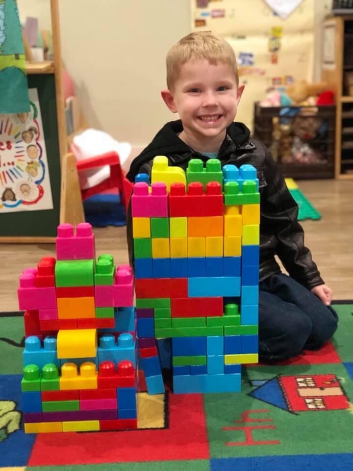 Child kneeling behind colorful building blocks