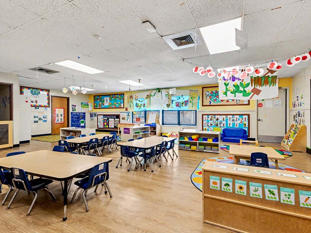 Empty classroom with small tables and chairs, colorful decorations on walls