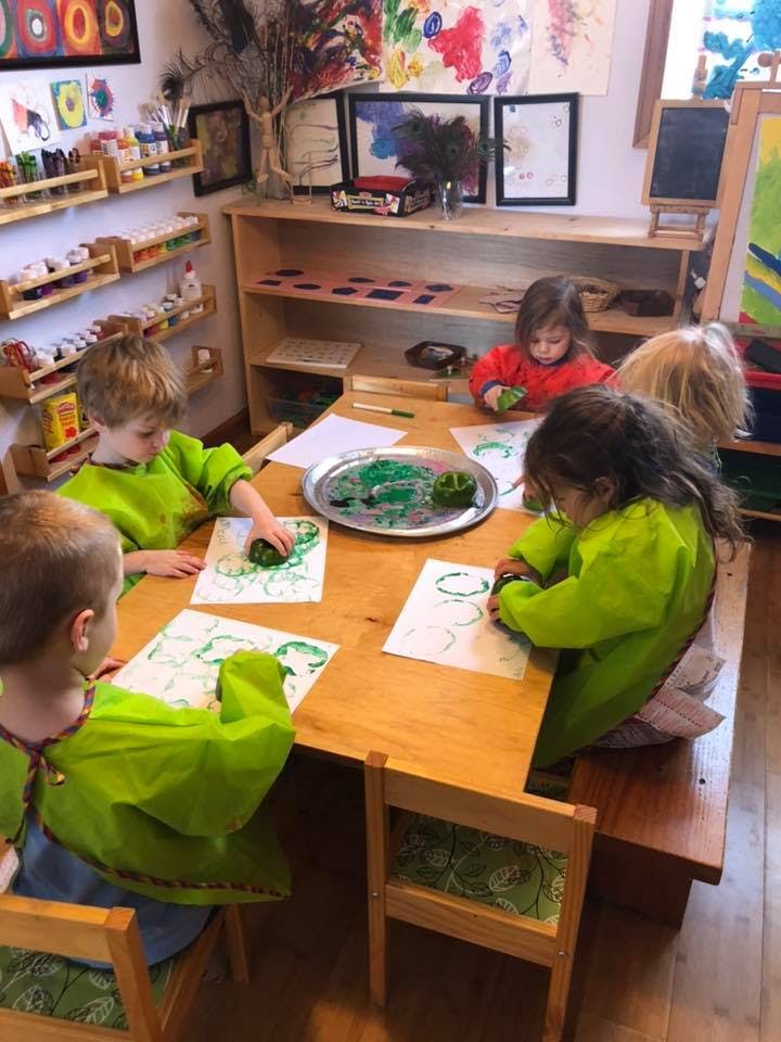 Children at a table doing an art activity with green paint