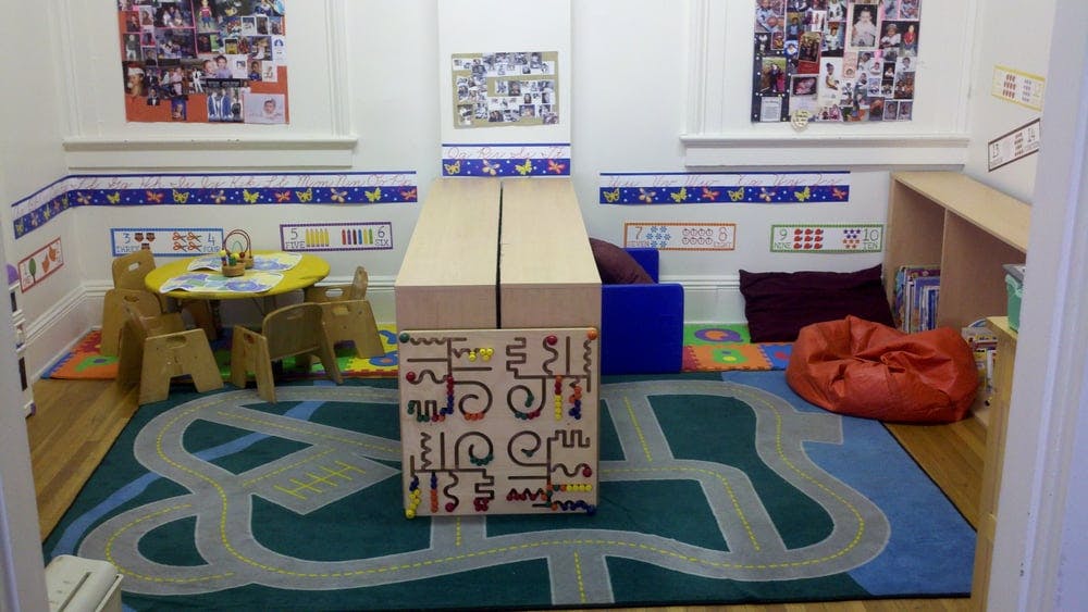 Playroom with small table and chairs, rug with road design, and toys