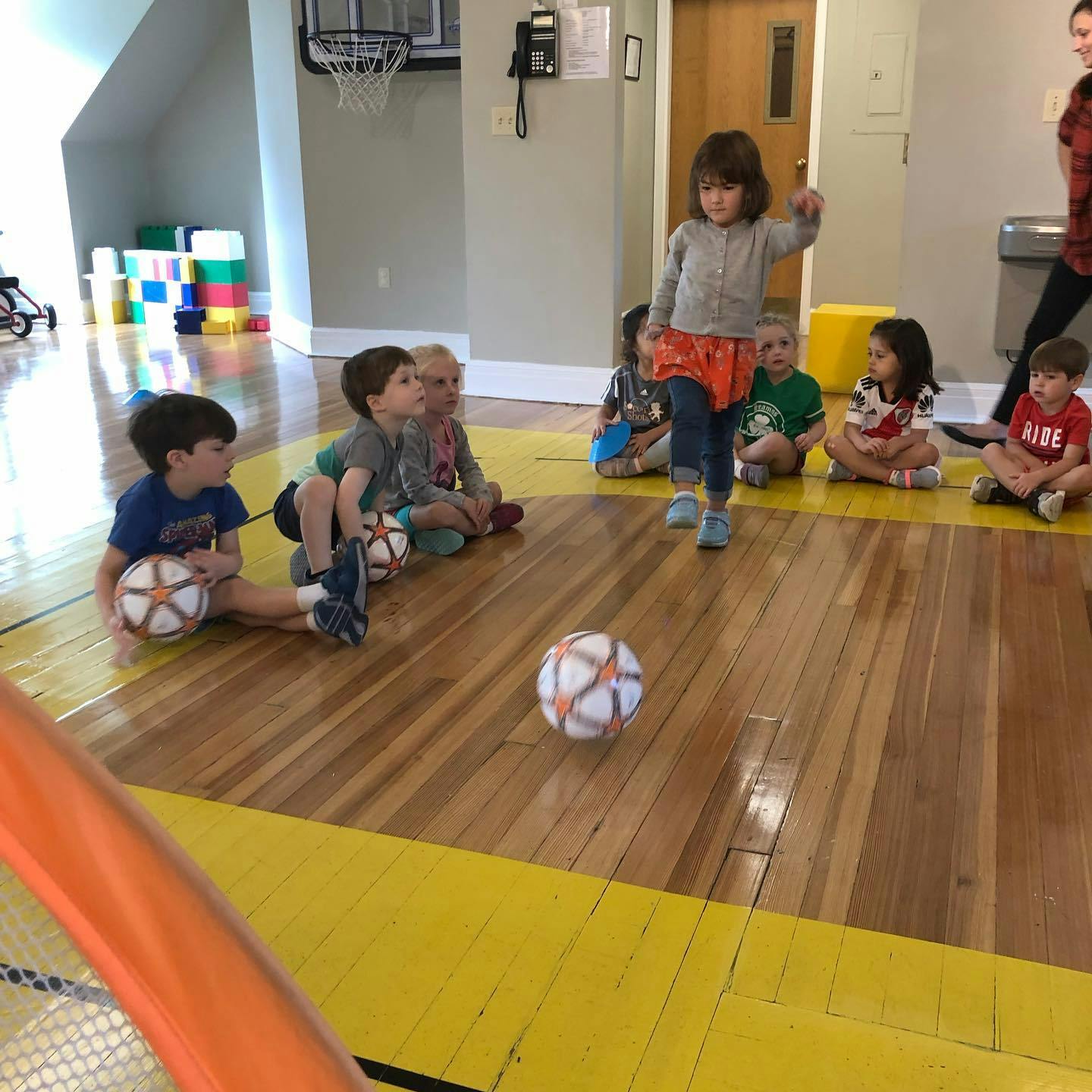 Children playing with soccer balls on a wooden floor
